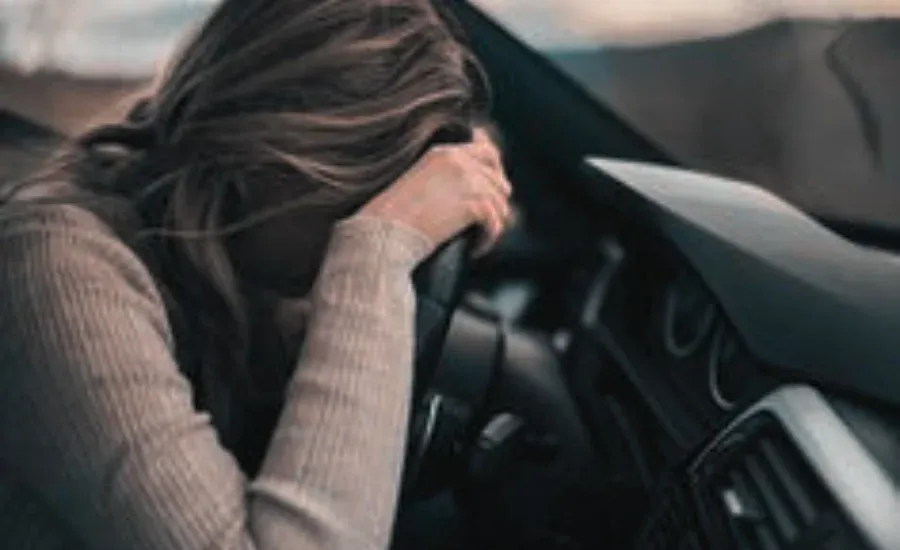 woman emotionally flooded crying in her car wheel