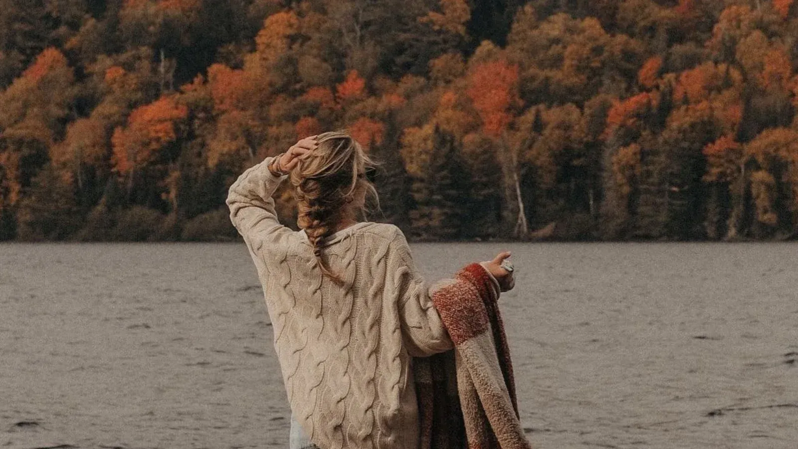 woman in the fall walking close to a lake