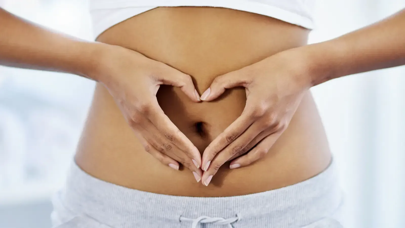 Woman forming a heart shape with hands over stomach for gut health and digestion