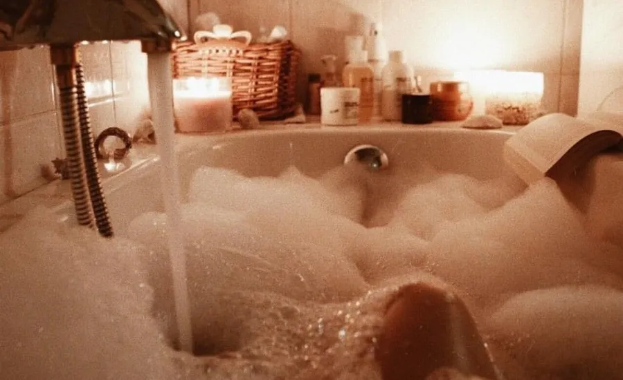 person taking a bubble bath with candlelight