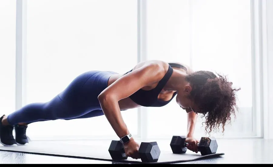 woman doing plank with barbels