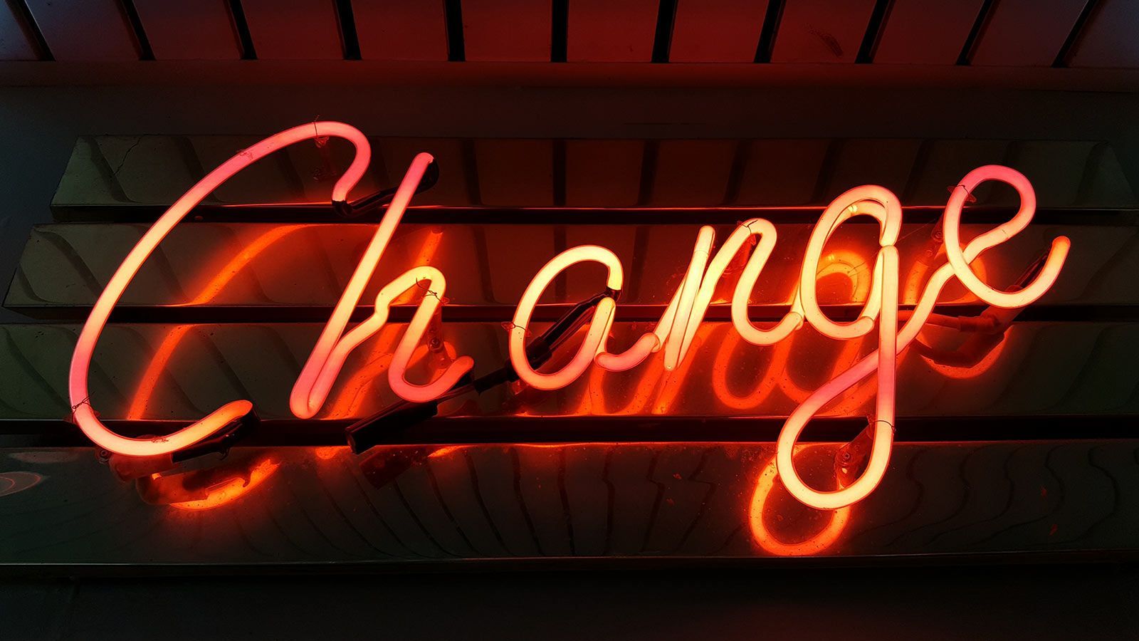 `Glowing red neon sign spelling the word "Change" against a dark textured background`