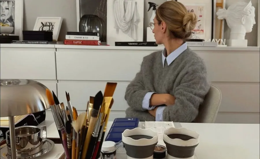 Woman sitting in a creative design studio with makeup brushes and art books on the desk