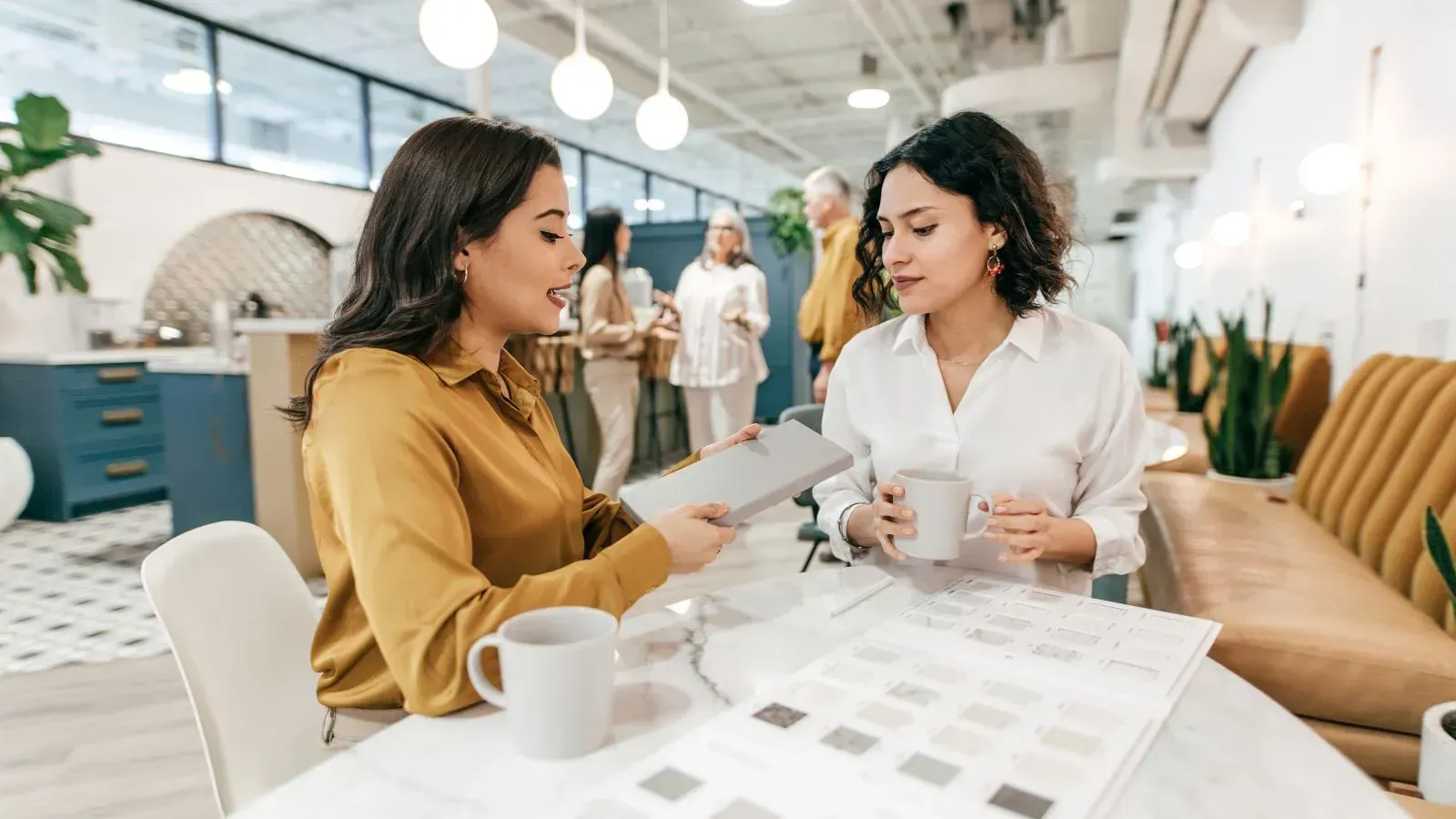 `Two professional women discussing notes and documents at a modern office table`