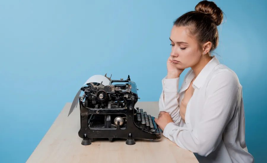 Woman seating in desk in front of a typewriter